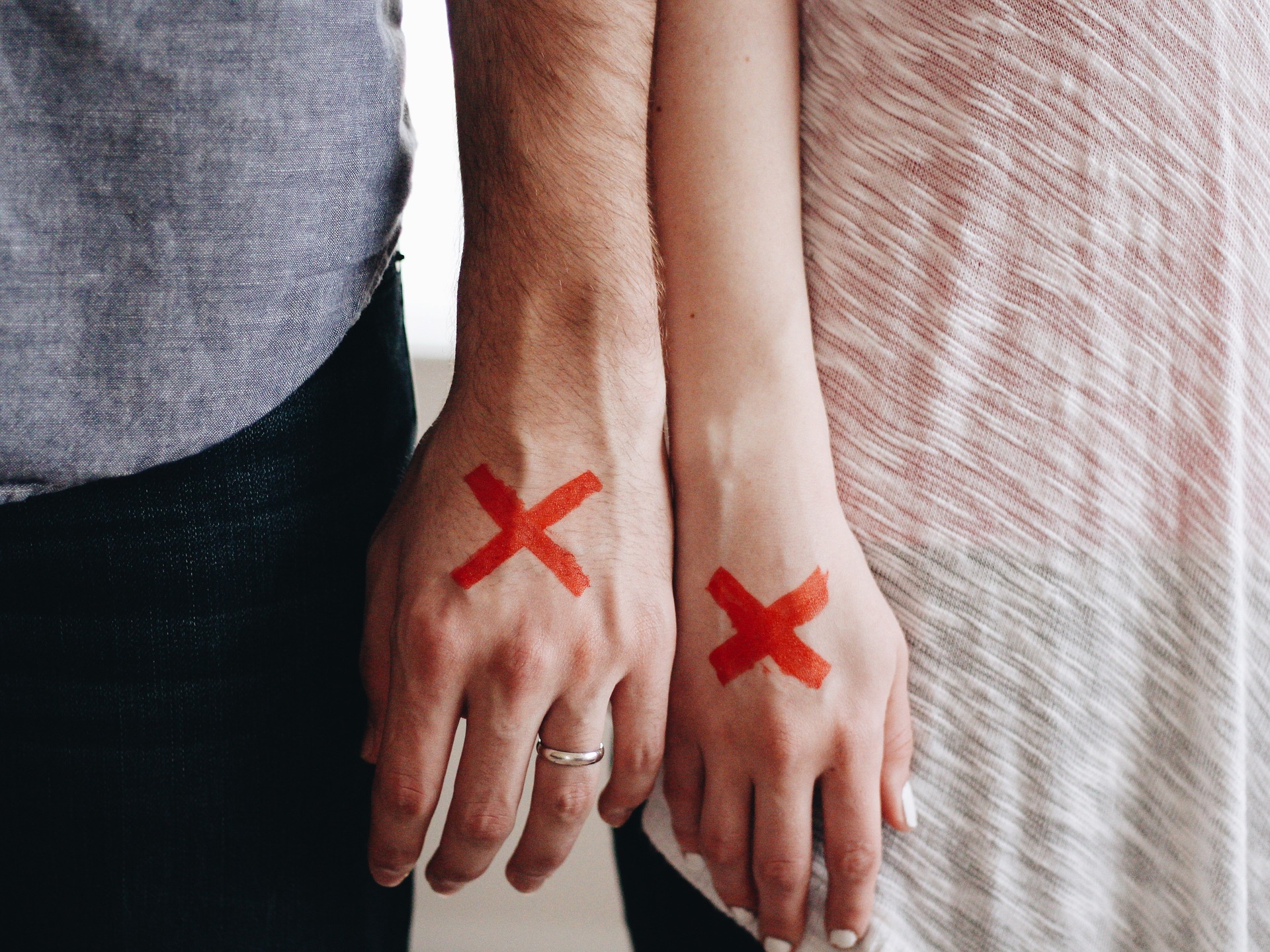 dłonie mężczyzny i kobiety, na każdej z nich namalowany czerwony krzyżyk - symbol rozwodu